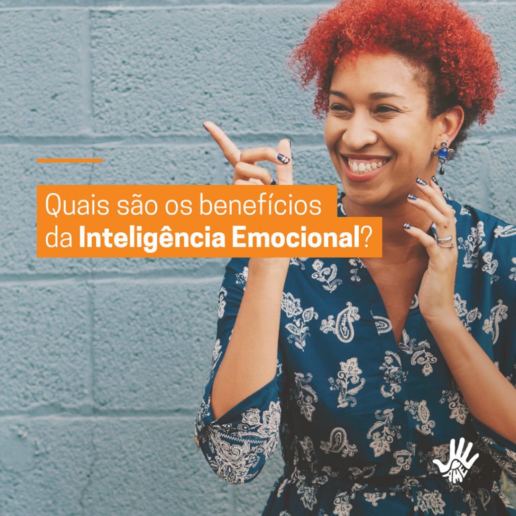 No lado direito da tela: Texto Quais são os benefícios da Inteligência Emocional? Do lado esquerdo: Mulher negra de cabelos vermelhos sorrindo com o dedo indicador da mão esquerda levantado