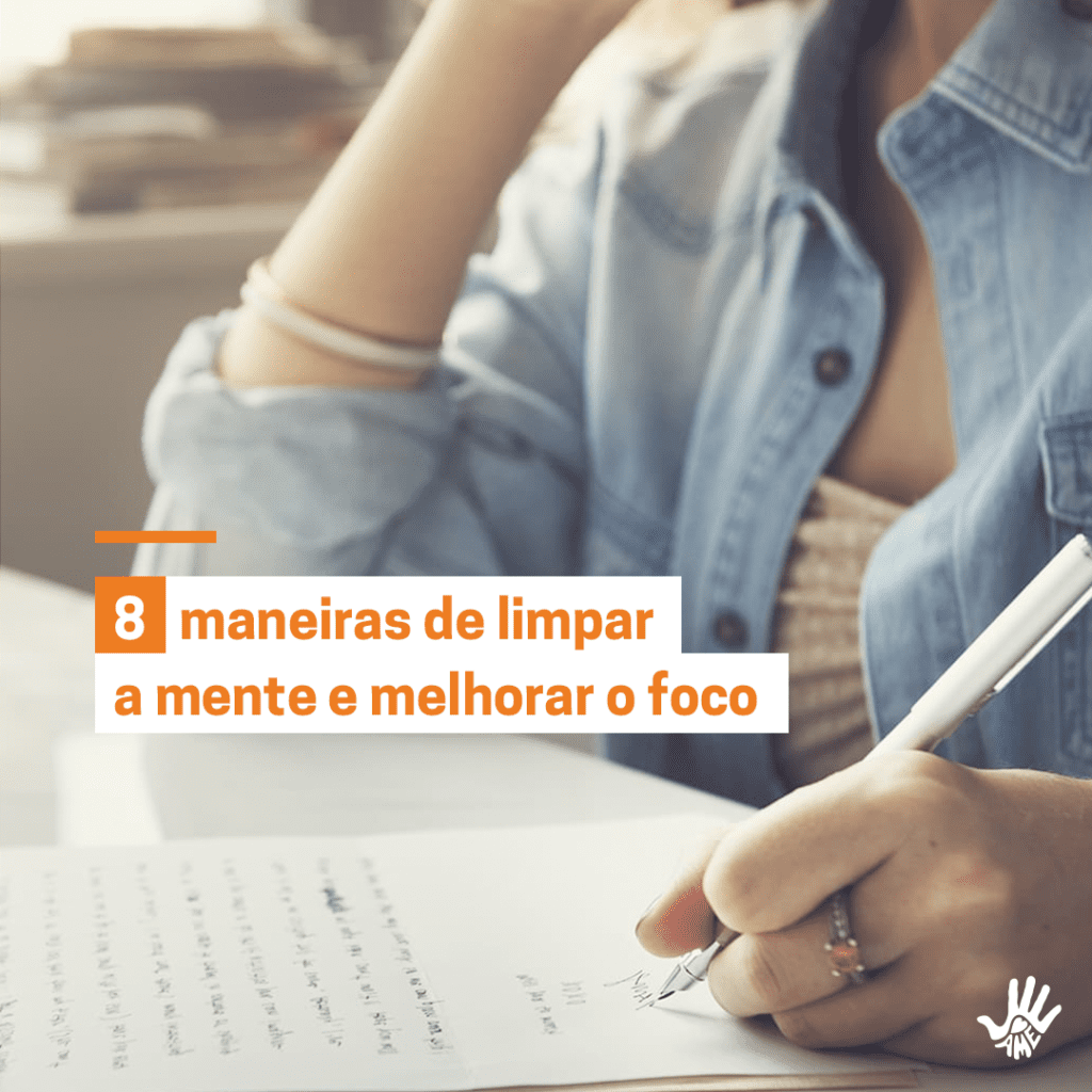 Pessoa vestida em camisa de botão jeans, aberta, mostrando o decote de uma blusa rosinha claro. Ela está sentada em uma mesa, com um braço dobrado em direção ao rosto e a outra mão segurando uma caneta que encosta em um papel sobre uma mesa branca, à sua frente. Texto alinhado à esquerda, em letras laranjas e fundo branco: "8 maneiras de limpar a mente e melhorar o foco"