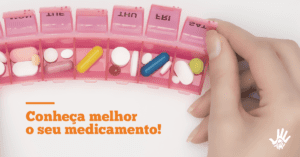 No topo da imagem, uma caixinha de plástico de guardar medicamentos com vários compartimentos. Todos estão abertos e contêm várias pílulas dentro de cada. Uma mão branca segura o último compartimento da direita aberto. No canto inferior esquerdo, o texto: "Conheça melhor o seu medicamento! Ofatumumabe aprovado pela Anvisa: saiba mais sobre essa nova opção"